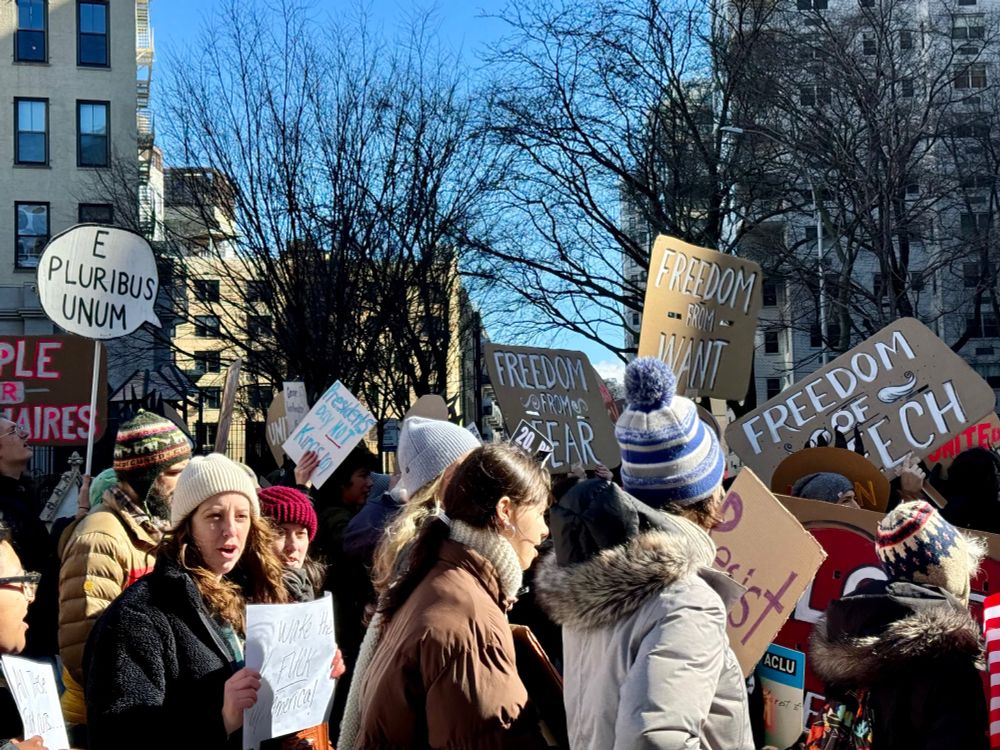 a closeup of some of the protesters on Broadway with signs that say E PLURIBUS UNUM, FREEDOM FROM FEAR, and FREEDOM FROM WANT