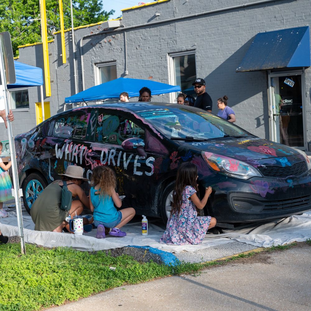 Children decorate a black sedan with paint
