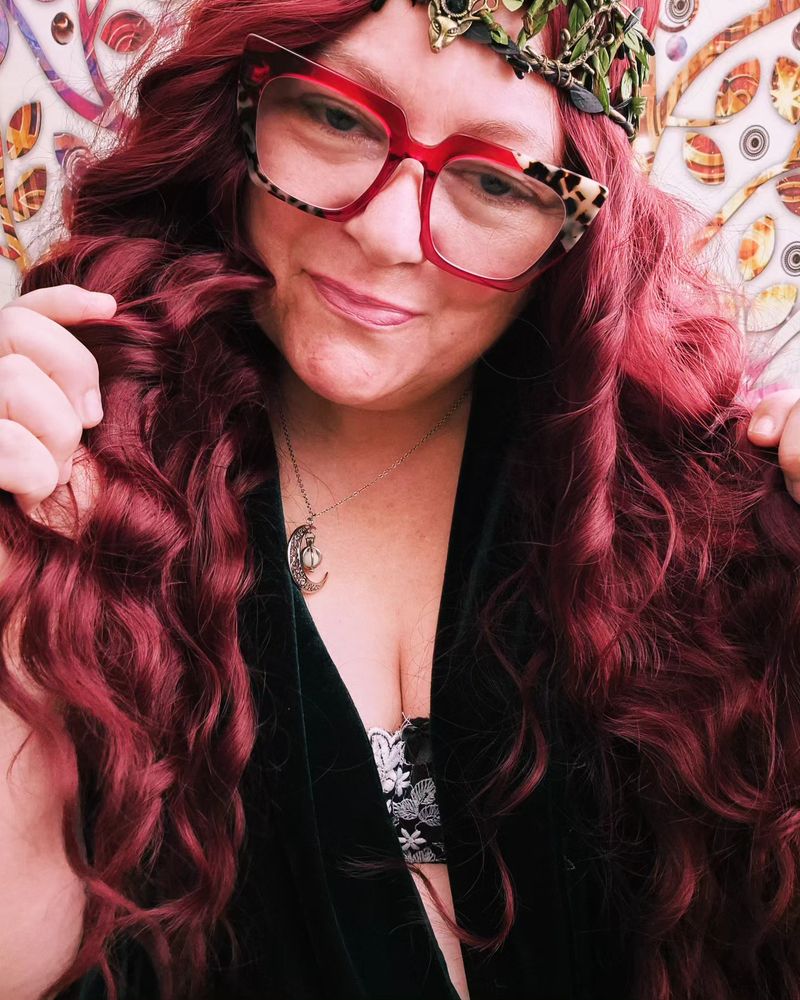 Curvy gilf redhead, looking teasingly at you. Wearing a gown and an ethereal crown. FINDOM 