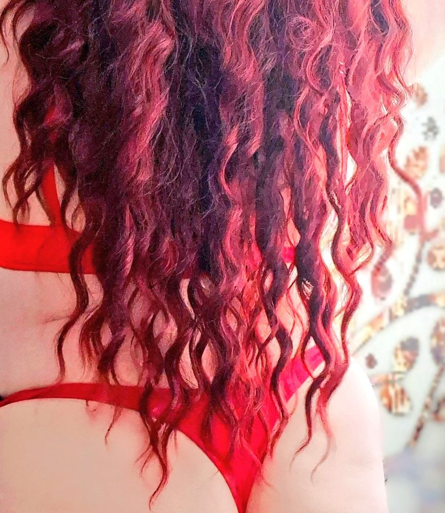 Bodouir photo of a model with perky bottom in a red thong, with long red curly hair flowing down her back 