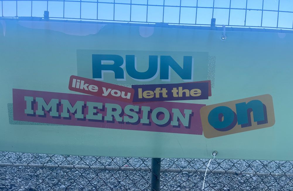 A sign on a fence that reads: ‘Run like you left the immersion on.’