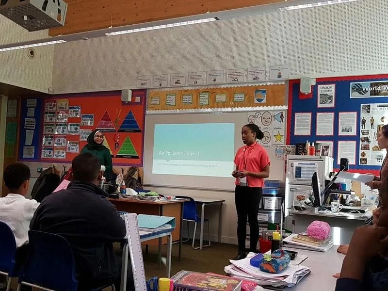 A UCL Chemistry undergraduate guiding a lesson on air pollution in front of a class of year 5 children.