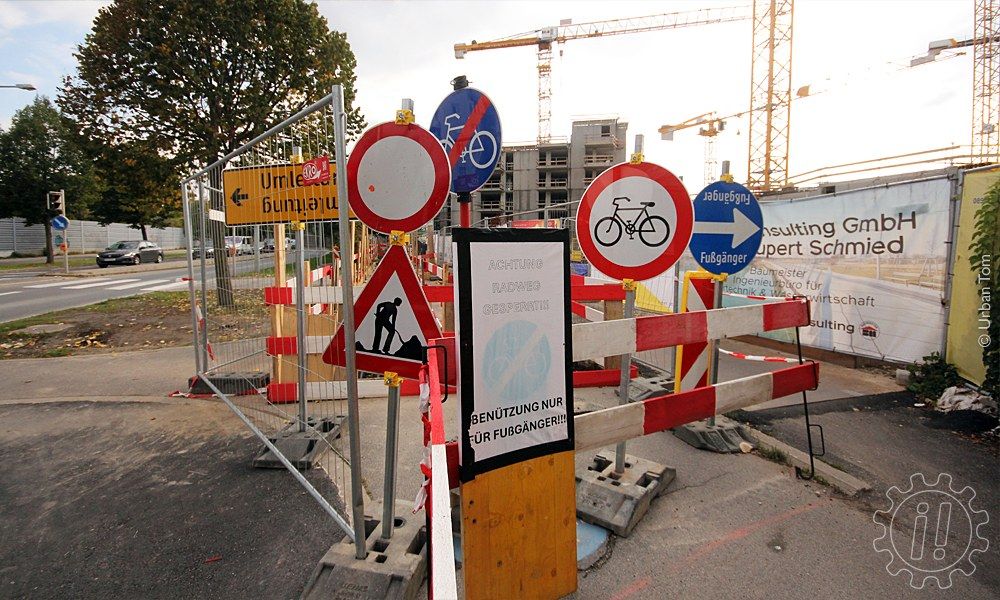 Vor einer Baustelle beim Donaufeld, durch die der Geh- und Radweg auf etwa 100 m Länge nicht in der vollen Breite verfügbar ist, stehen sieben Schilder: Umleitung (nach links), Fahrverbot, Baustelle, Ende des Radwegs, Fahrverbot für Fahrräder, Fußgänger (rechts gehen) und ein aufgeklebter Ausdruck mit dem Text "Achtung Radweg gesperrt!!!" über einer blassen Grafik "Ende des Radwegs" und darunter "Benützung nur für Fußgänger!!!"