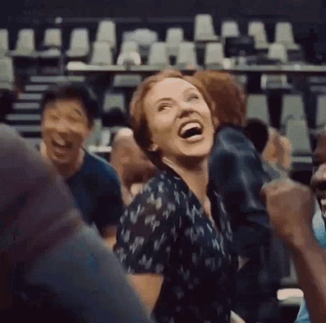 a woman is laughing in a crowd of people in a theater .