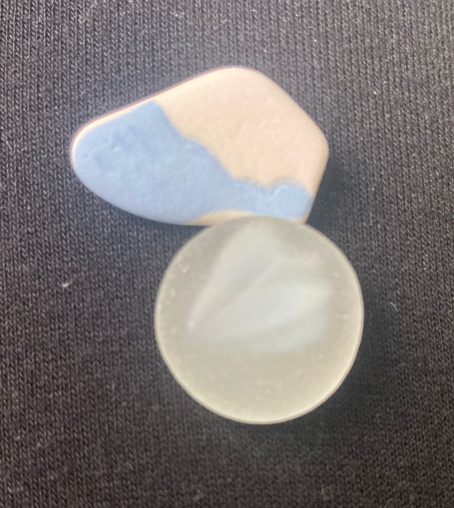 A light blue and white piece of pottery, and a clear piece of glass with white inside it. 