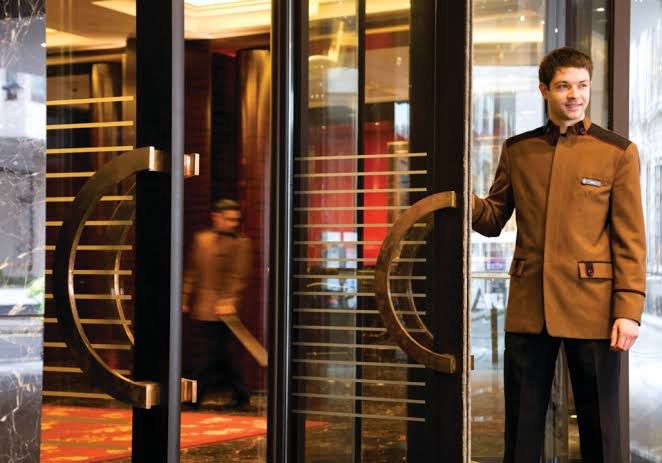Hotel doorman holding a door open. 