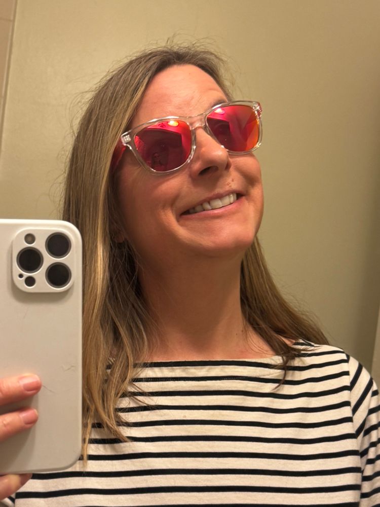 Woman in pink and orange mirror sunglasses and cheesy grin 