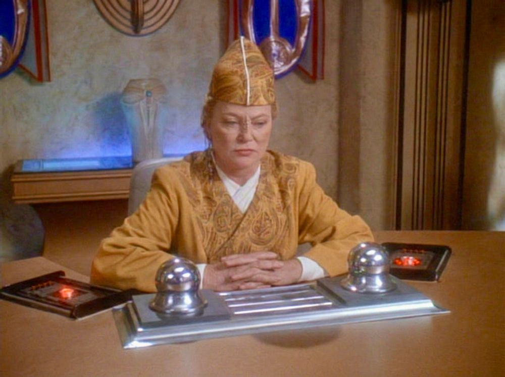 the kai from DS9 with mysterious knobs and console and padds on her desk. 