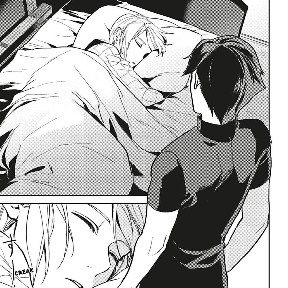 A manga illustration, showing a man with dark hair standing over the bed of a sleeping man with fair hair, looking down at him.