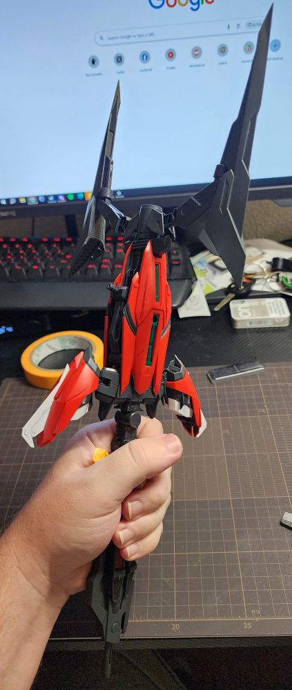 A photo of the Tactical Arms II-L being held in my hand. It is red and Grey with white accents, and is the size of a small sword relative to my hand. 