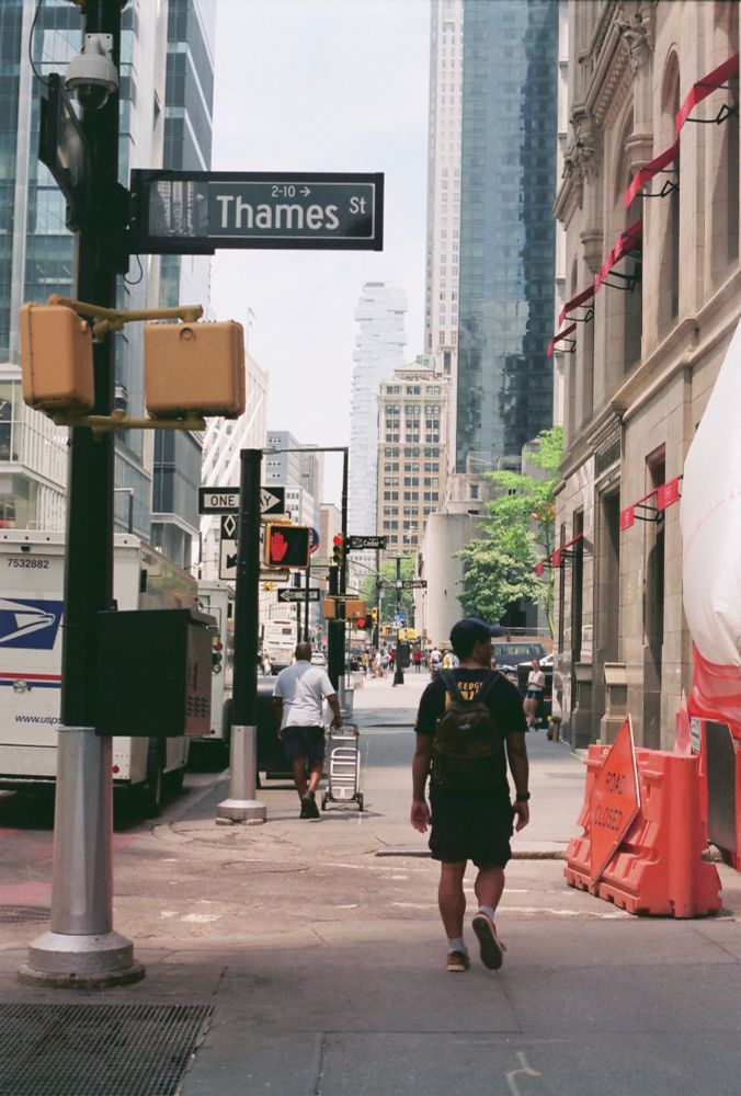 A man turned away from the camera walking down the street in NYC