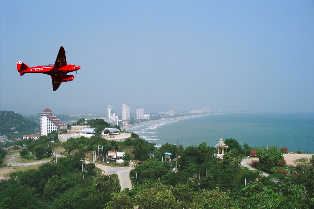 De Havilland's famous Comet Racer (painted bright red), winner of the 1934 England - Australia air race, flying over Hua Hin in Thailand