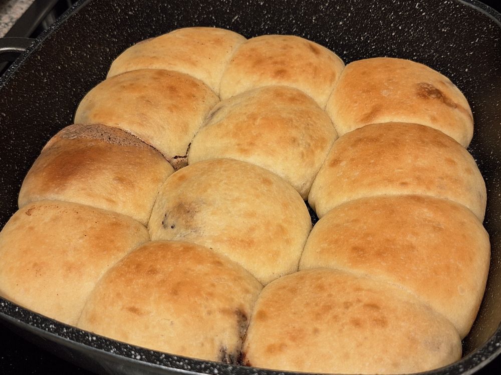 Eine viereckige Pfanne in der 12 goldbraune Buchteln dicht an dicht liegen.