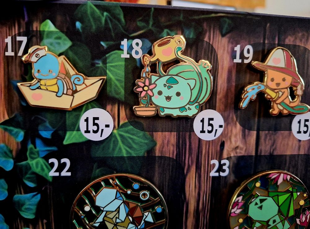 Total niedliche Pokémon-Buttons. Schiggy mit Matrosenmütze auf einem Papierboot, Bisasam gießt eine rosa Blume, Glumanda als Feuerwehrmann.