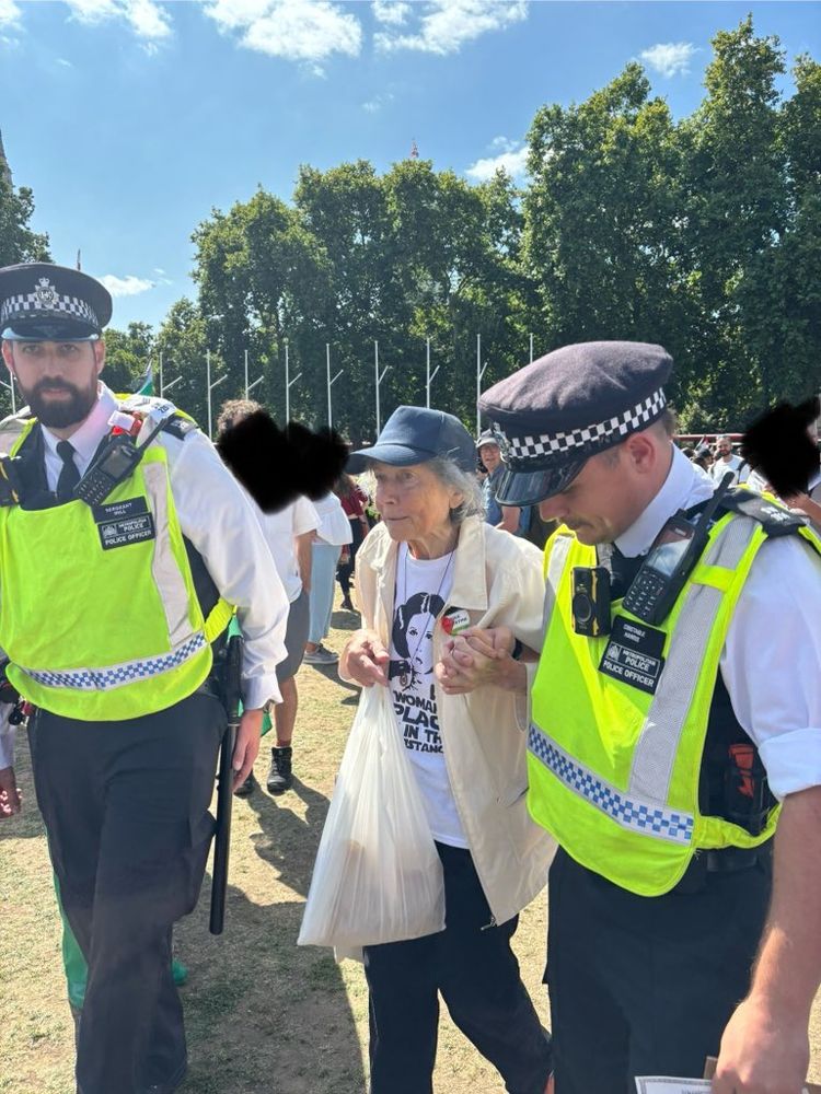 Two police officers arrest and escort an elderly female protester at an anti Gaza genocide rally