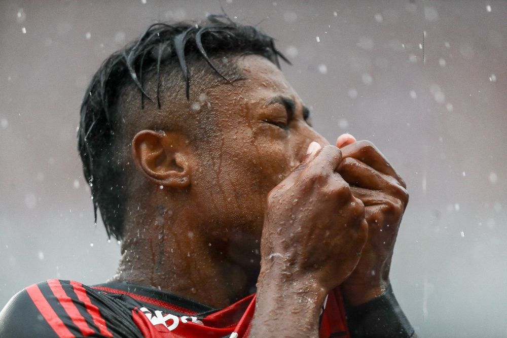 Bruno Henrique beija o escudo do Flamengo enquanto cai a chuva