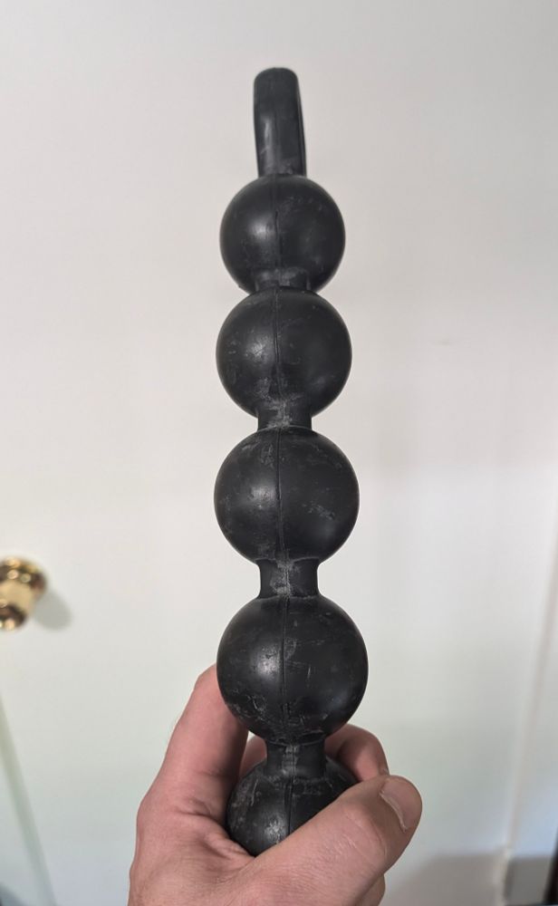 Image of a long black rubber object in the shape of several spheres attached to each other in a line
