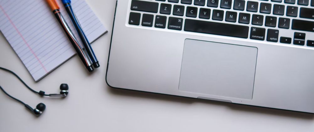 Laptop, headphones and notepad on a desk