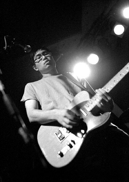 Sooyoung Park, a man who looks nothing like Steve Haruch, even though they are both Korean American, is wearing a white T-shirt while playing a Fender Telecaster guitar onstage. Park is/was the frontman of the indie rock band Seam, formed in Chapel Hill, NC, relocated to Chicago and active in the 1990s and early 2000s. 