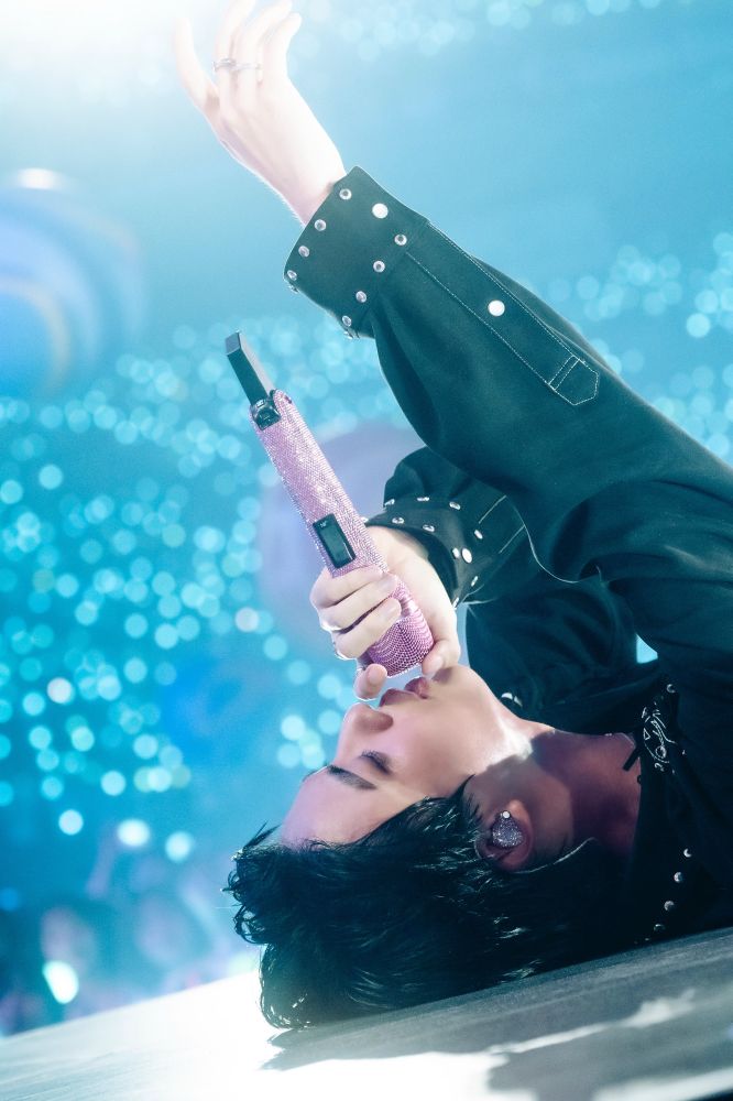 Seokjin lying on the floor, singing with his eyes closed and with one arm raised