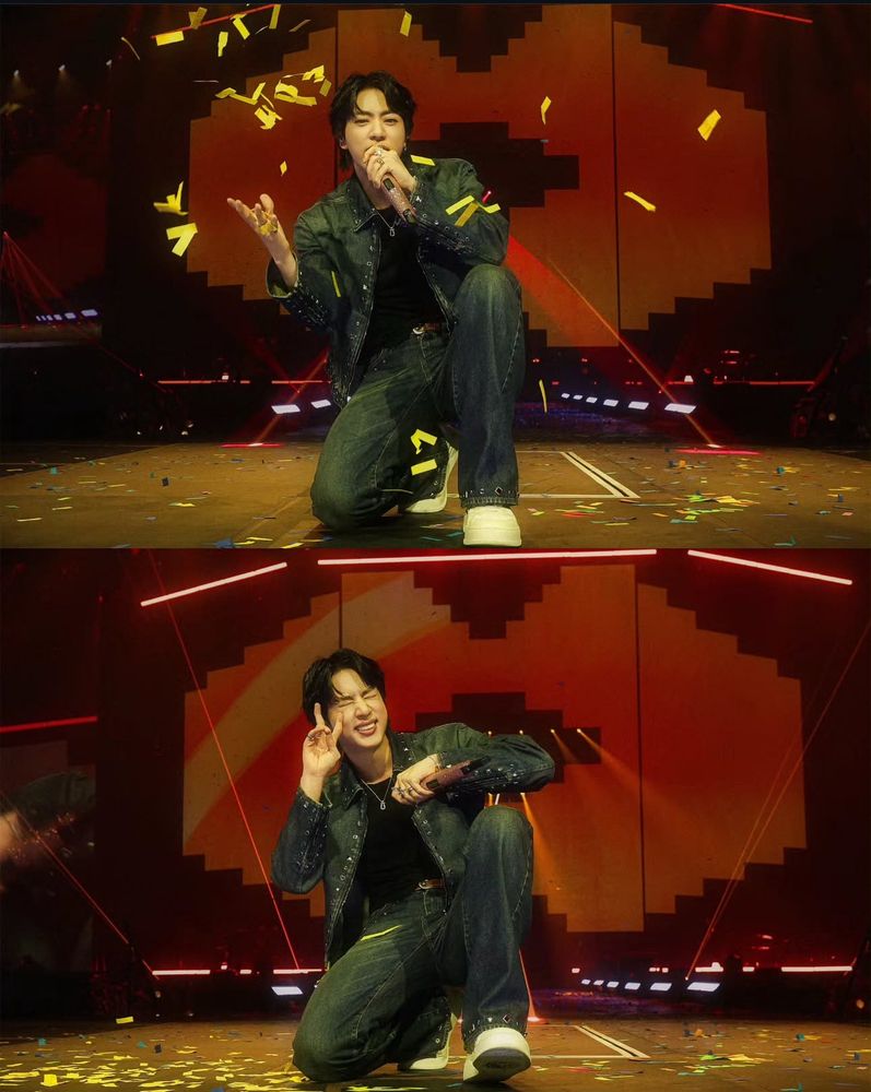 Seokjin kneeling on stage making a cute peace sign and winking
