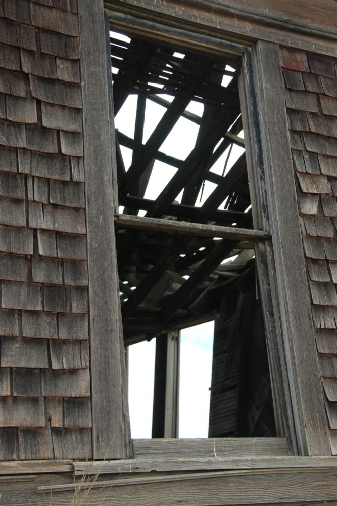 Interesting old decrepit schoolhouse with greyish brown weathered wood, collapsed roof on one side, it's "spire" has tipped over at an angle, and interior has evidence of many kegger parties (spray painted graffiti, detritus). It is unsafe to enter, and the front porch and stairs are gone.