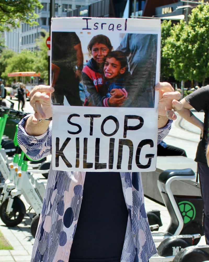 Placard reads: Israel Stop Killing 

There’s a photo of two distraught Palestinian children in the centre of the placard 