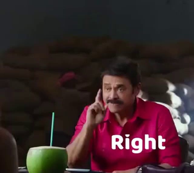 a man in a pink shirt is sitting at a table with a coconut and a straw .