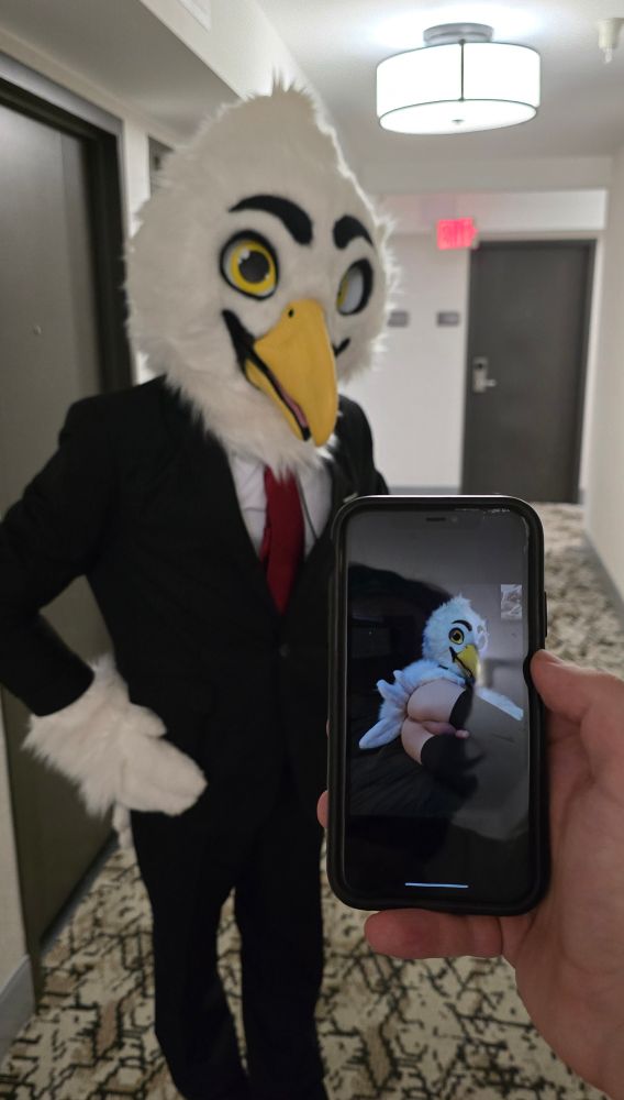 Ellis in full suit standing behind the viewer holding up their phone, with a picture of Ellis with his ass out on it. 

#murrsuit #AC2025 #FursuitFriday #nsfw #irlnsfw #anthrocon