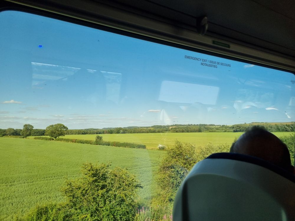 View from a train window looking out onto fields.