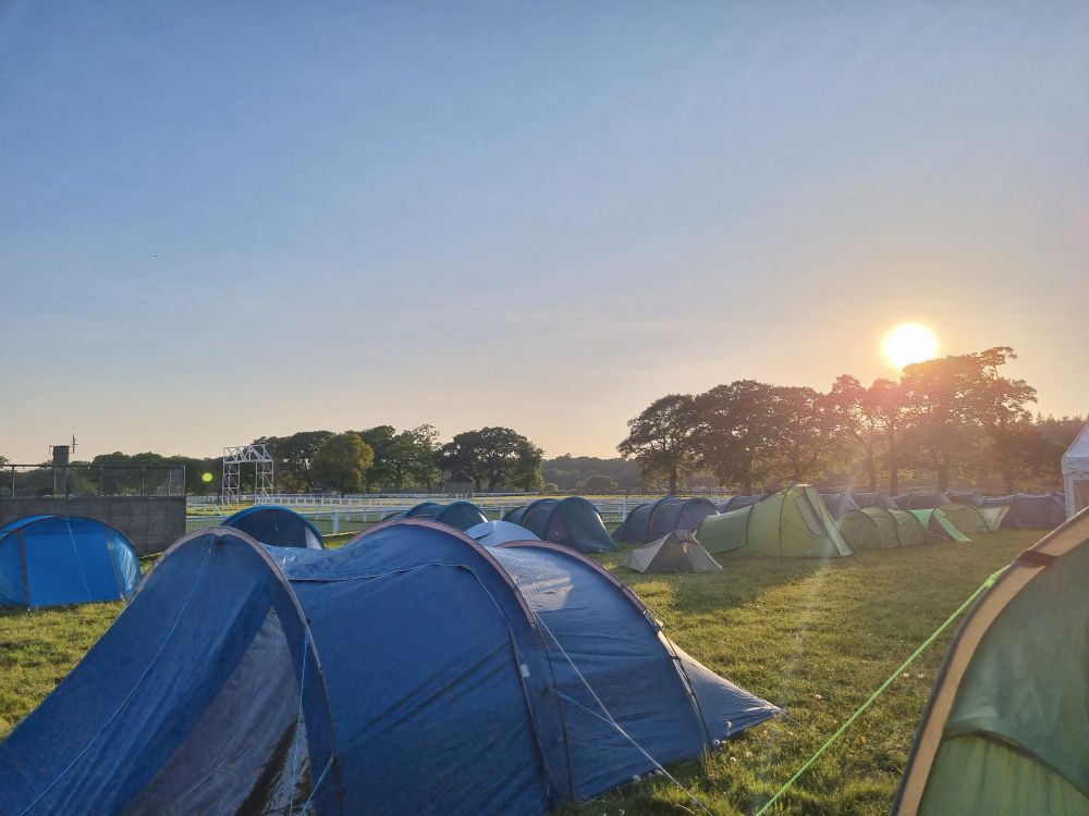 Camp site with the sun setting behind trees.