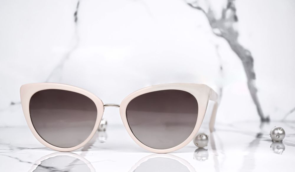 A pair of off white sunglasses in a marble room. 