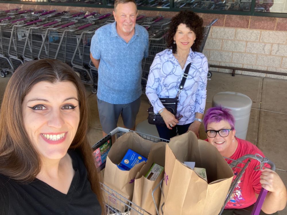 Danica and three volunteers from PWC Hunger Free pose for a photo in front of four paper bags filled with donated groceries from Danica at the Giant in Gainesville, Virginia.