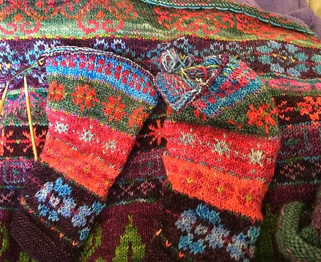 Closeup of a sweater, with intricate knitted floral patterns in magenta, orange, purple, and green