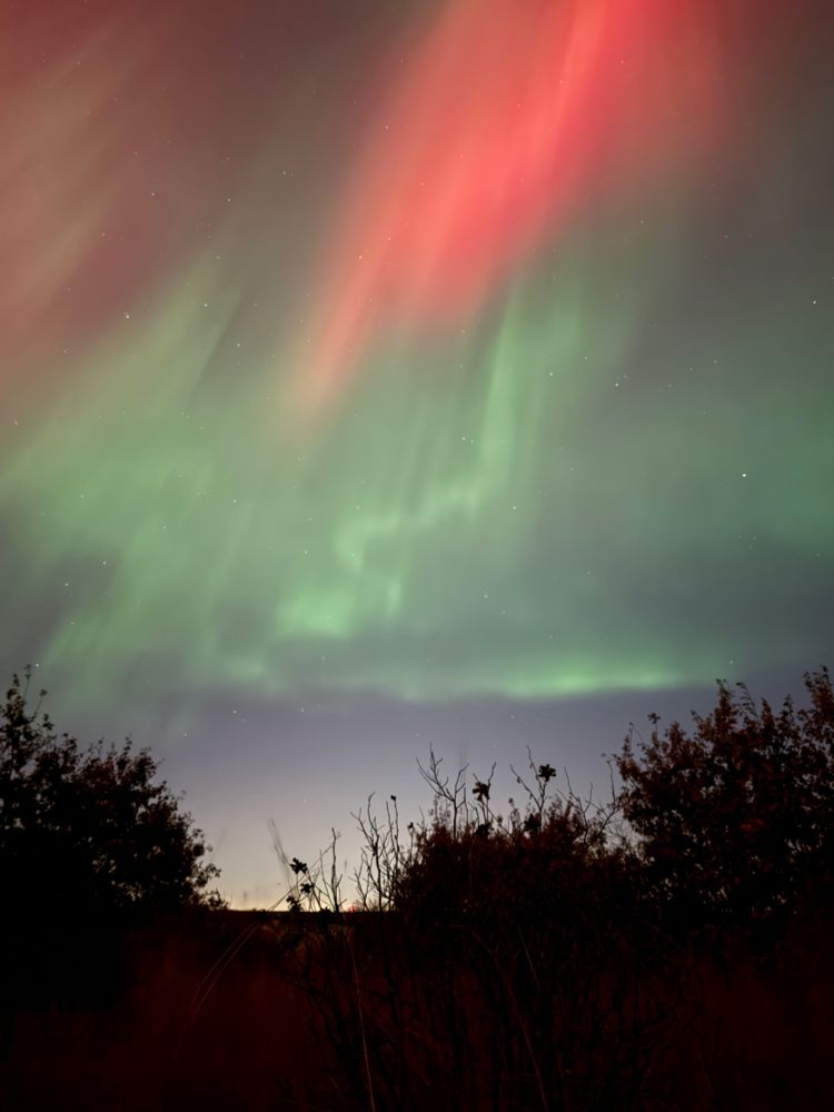 Wavy green aurora beneath a burst of red
