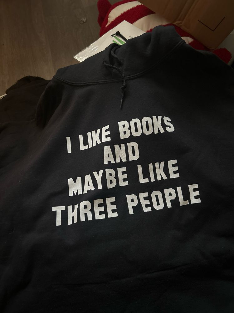 Black hoodie with white writing that reads I like books and maybe like three people 