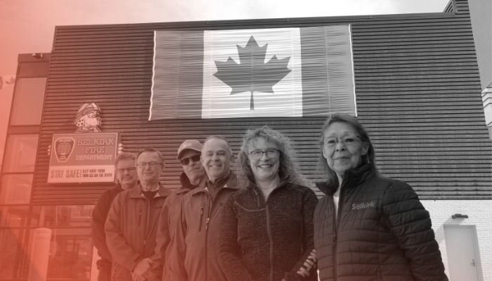 a black and white image of six people standing in front of the Canadian flag on the side of the Civic Centre