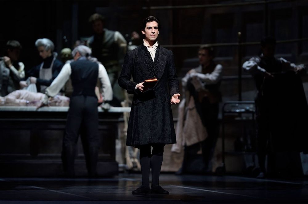 From the royal ballet’s Frankenstein. Viktor Frankenstein stands Center Stange in front of an autopsy table. He is holding a book. 