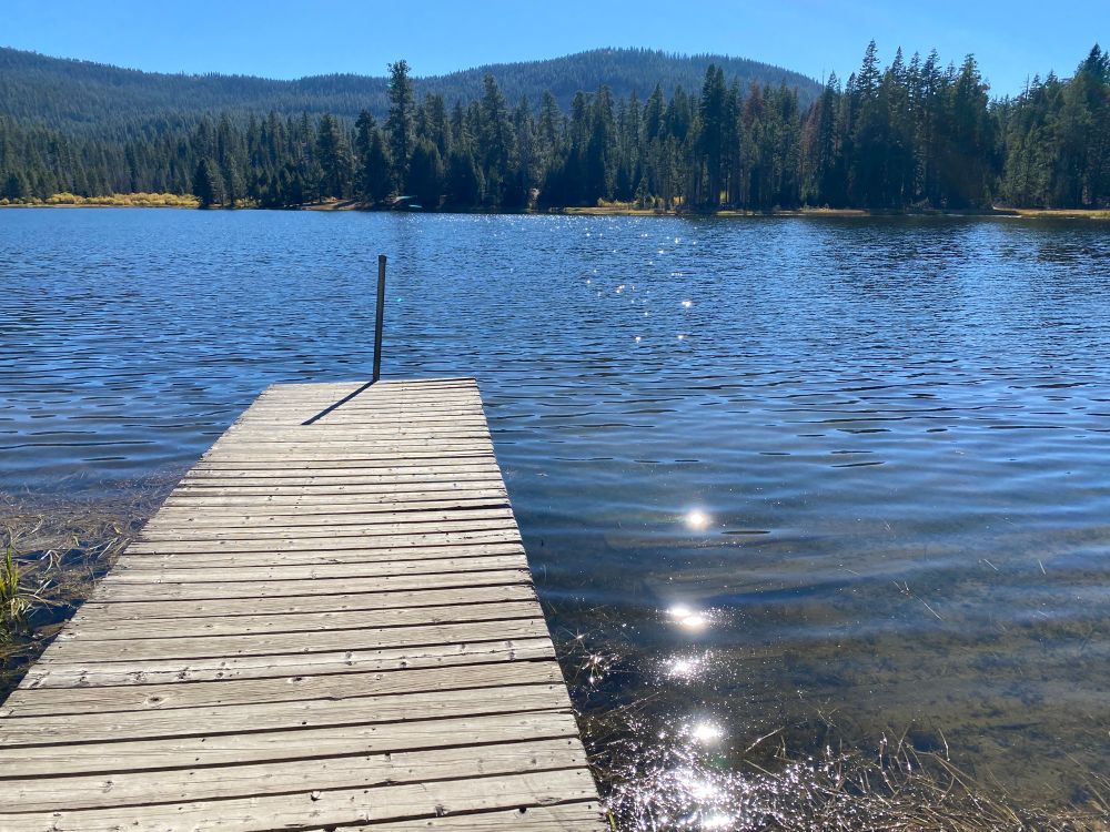 Sunlight reflecting on a mountain lake next to a floating dock 
