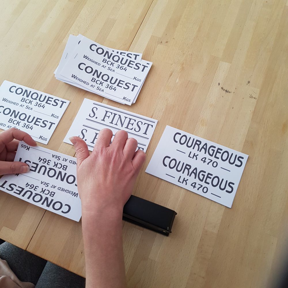 Piles of paper tickets being stapled together. Each pile has a different boats name Conquest, S. Finest and Courageous 
