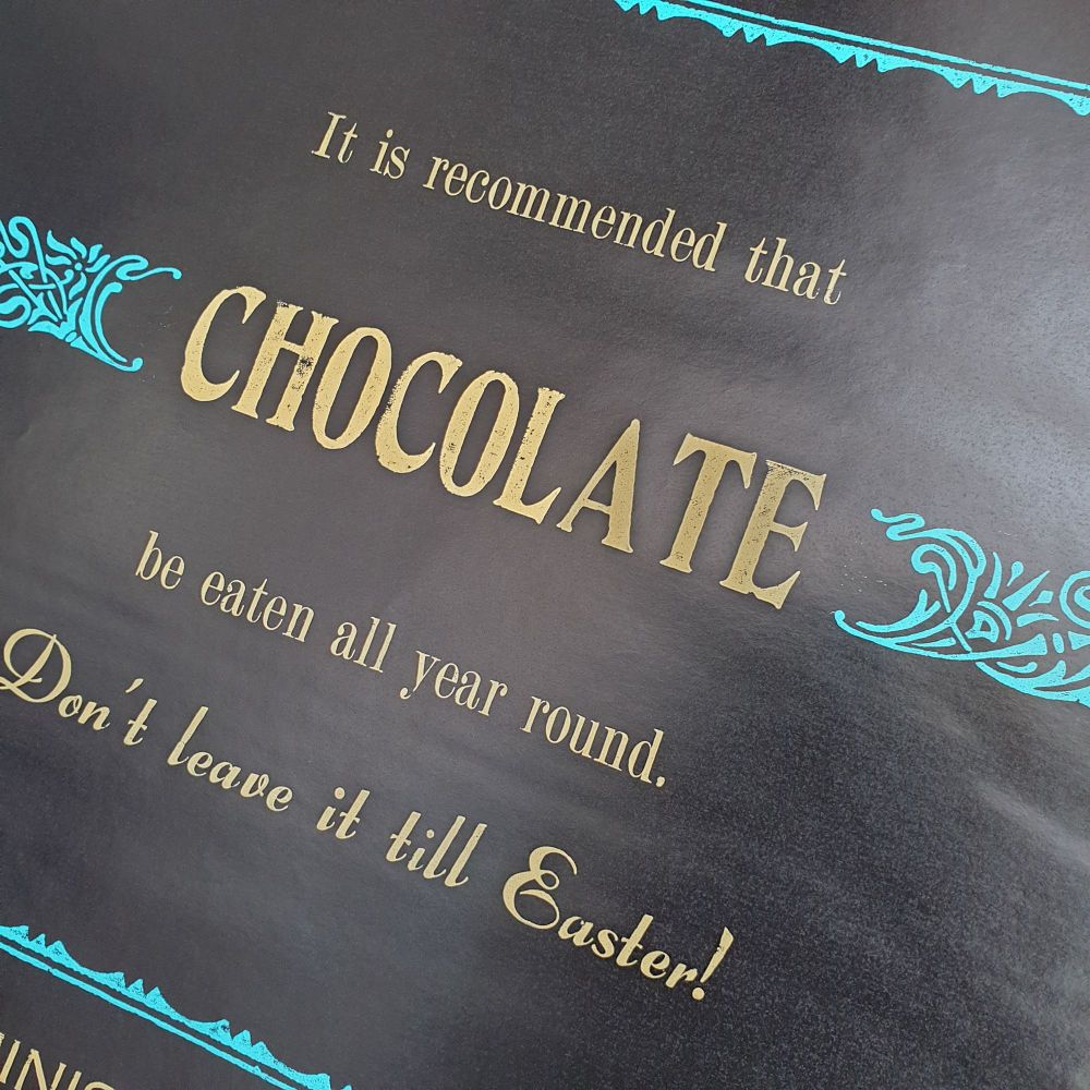 Text in cream reads it is recommended that Chocolate be eaten all year round. Don't leave it till Easter! Turquoise ornamental borders printed on black background. 