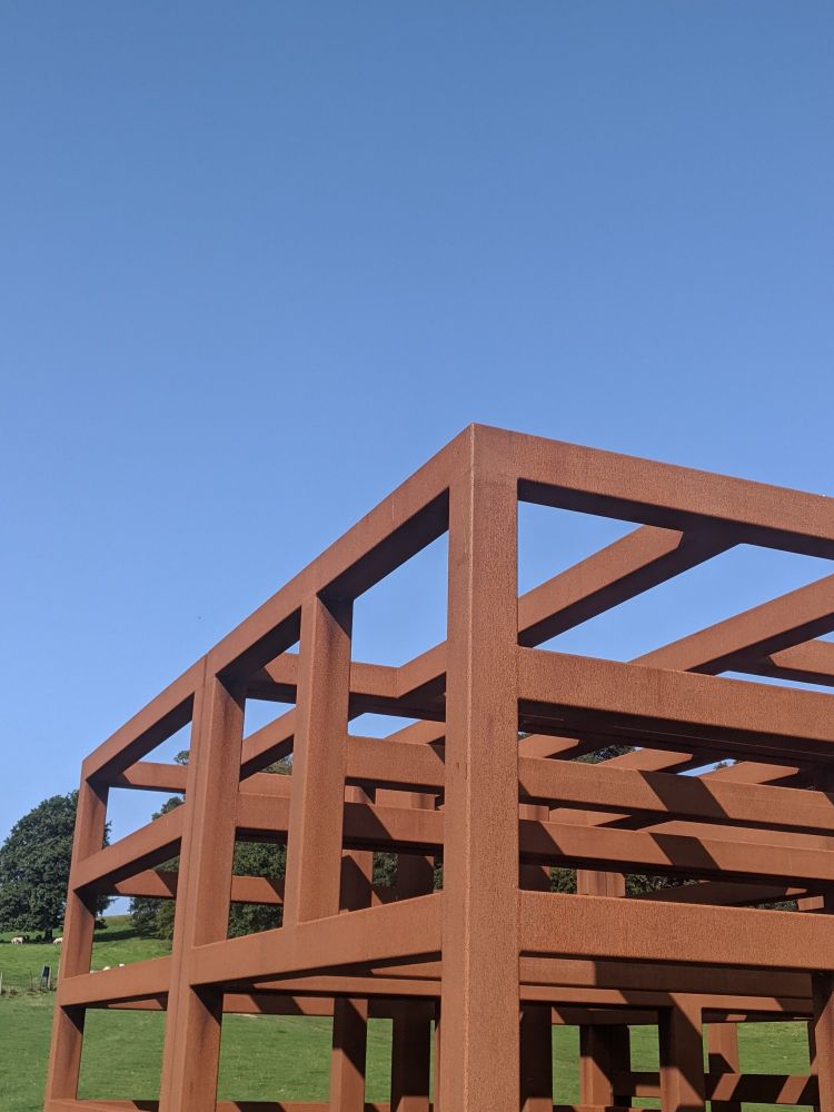 A weathered steel sculpture against a blue sky 