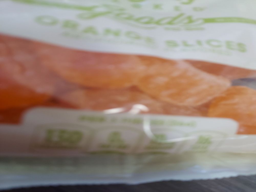 A blurry image of gummy fruit slices in tan packaging