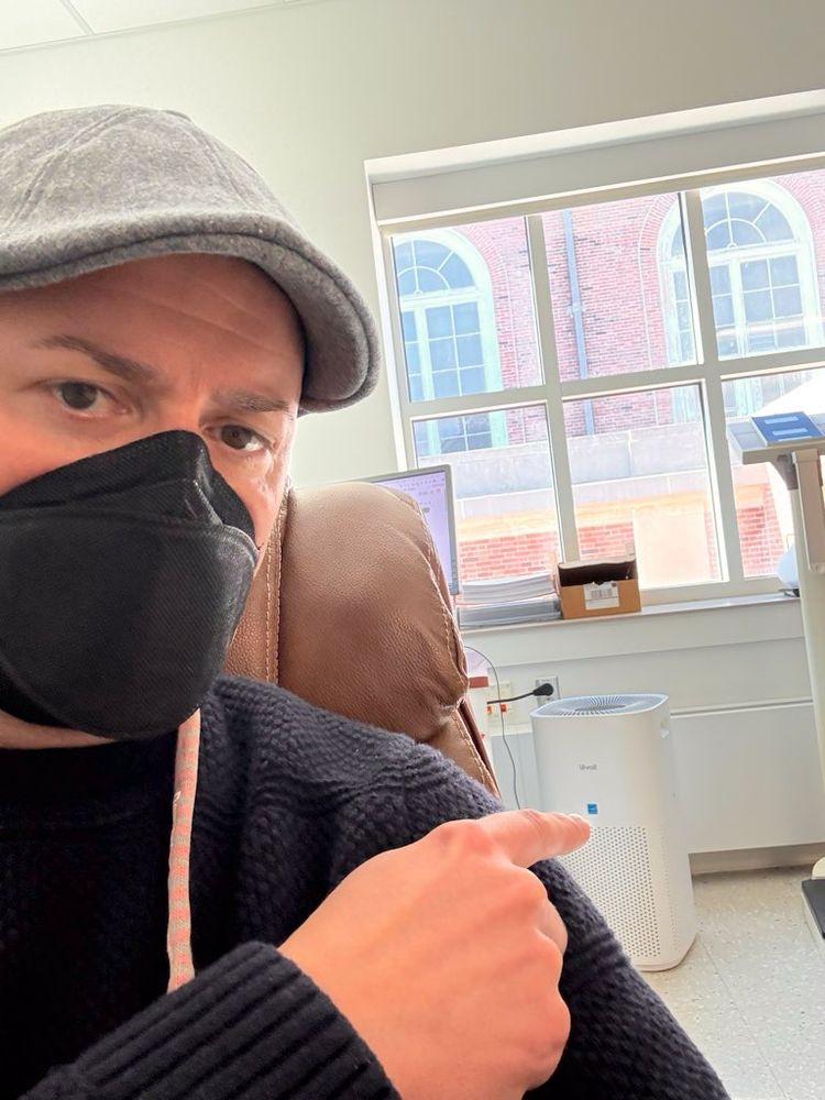 Dr Sean Mullen in his lab wearing a CAN99 Vitacore respirator and pointing to a Levoit 600 air purifier.