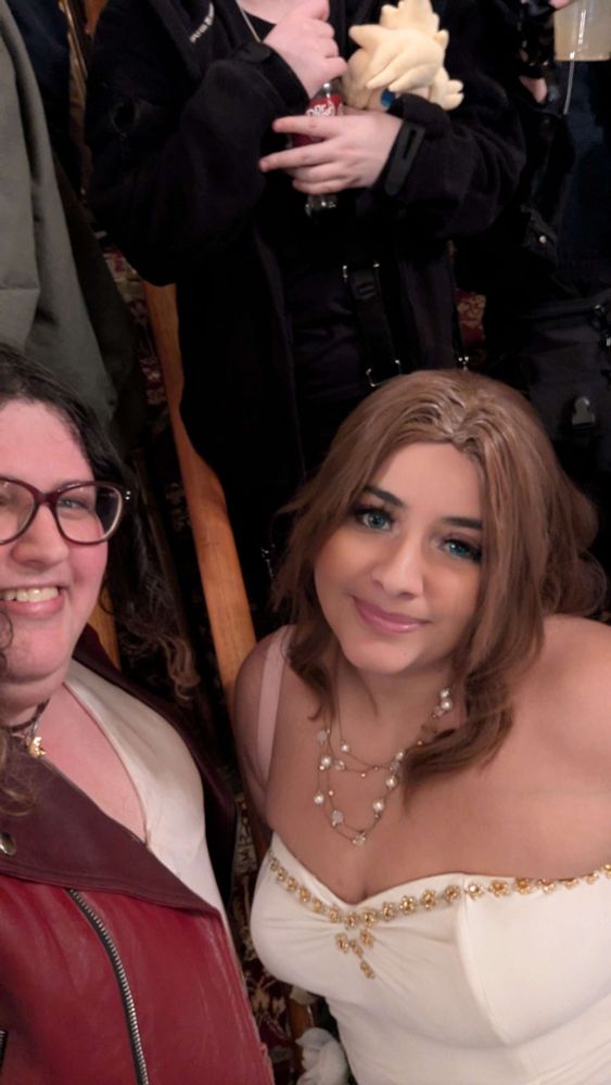 A selfie of two people cosplaying Aerith's normal outfit and her Gold Saucer sequence outfit