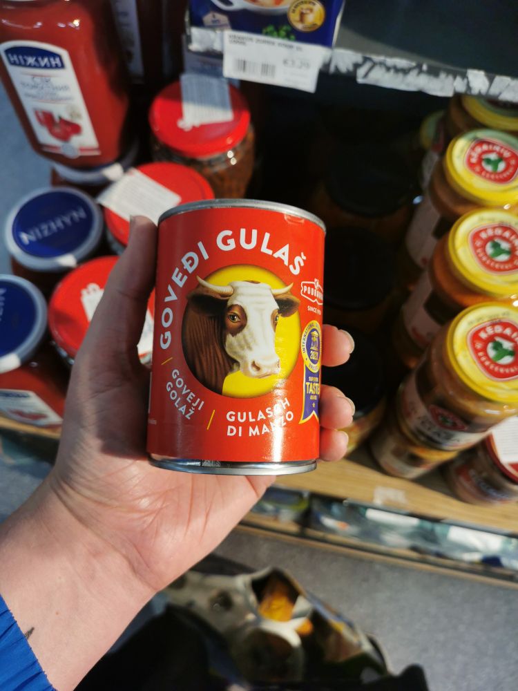 A hand holding a can of beef tushunka