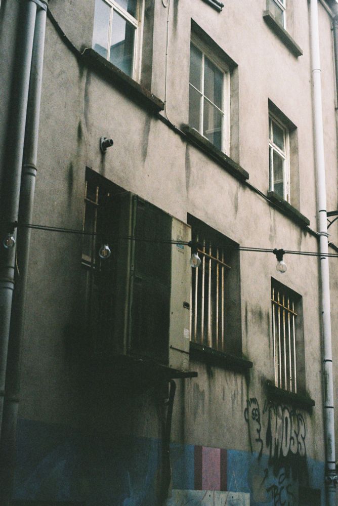 A Film Photograph of an Alleyway with Graffiti of a character with text reading ''MOSS'' right next to it.