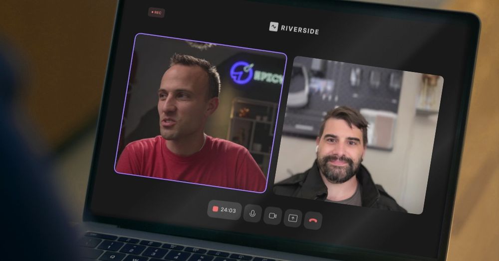 A laptop screen displays a video call on the Riverside platform featuring Kent C. Dodds on the left and Zachary Jackson on the right. Kent is wearing a red shirt and speaking with a focused expression. His background includes a glowing “Epic” sign and shelves with decorative items. Zachary has dark hair, a beard, and is wearing earbuds while smiling slightly. His background features a workspace with tools mounted on the wall. The call has been recording for 24 minutes and 3 seconds, as indicated by the timer at the bottom of the screen. The interface shows recording, microphone, camera, and call controls.