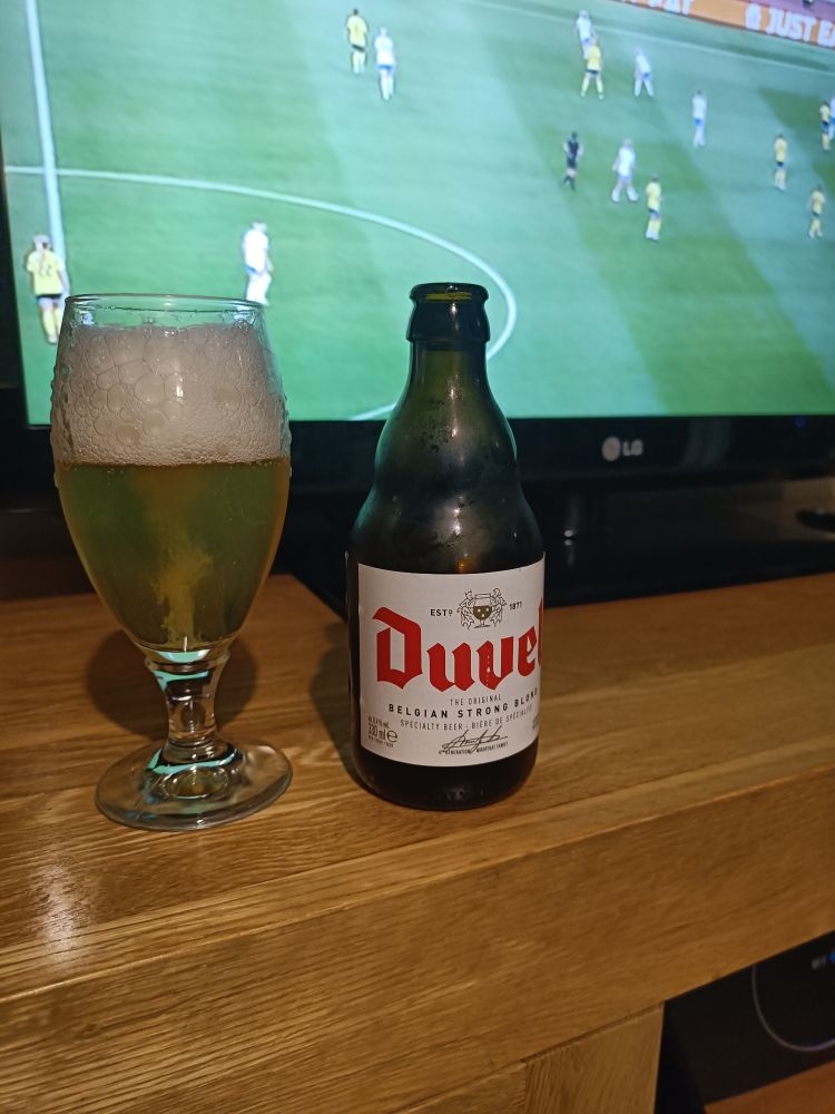 The beer is served in an old Stella chalice. I really want a Duvel glass. The bottle is iconic Belgian with a white label with red logo and various writing.
No tasting notes on the label.
Alc 8.4% vol.
Lady football in the background.
