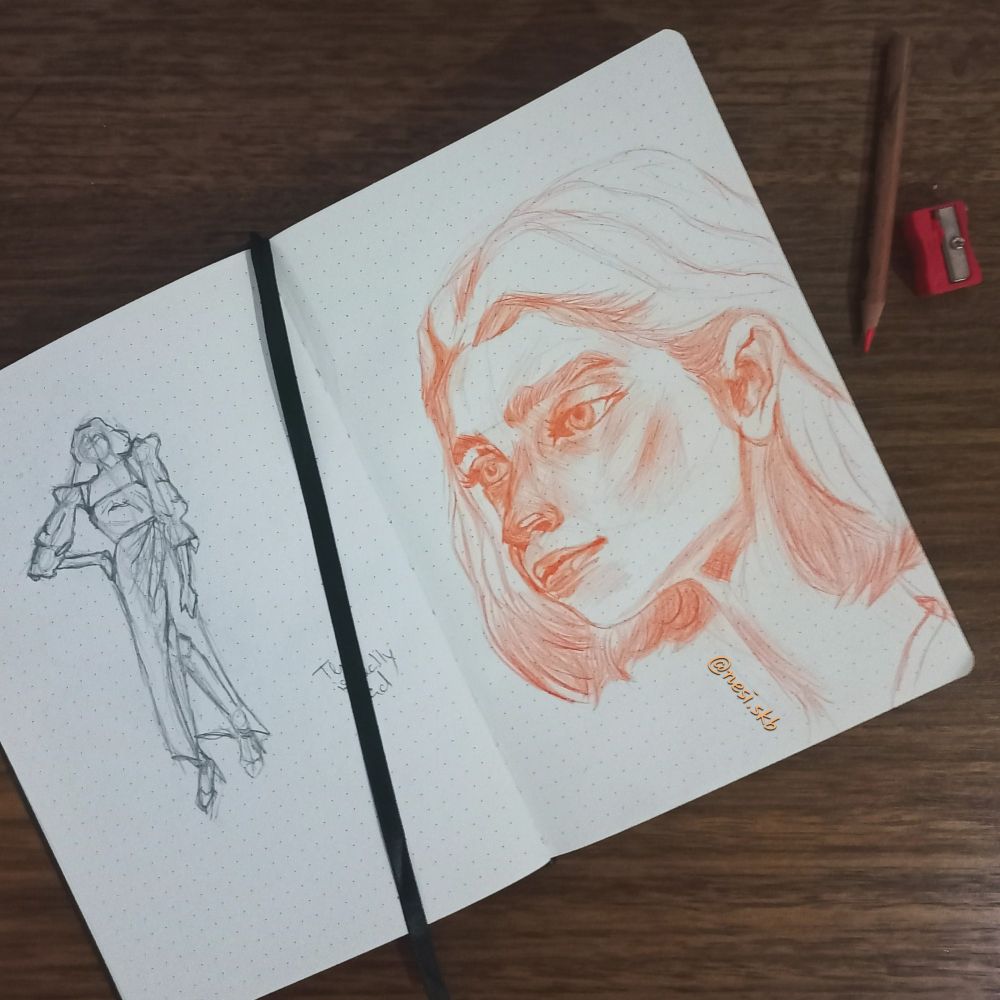 Sketchbook with a drawing of a girl's portrait on the right page and an attempt at drawing clothes on a figure on the left page